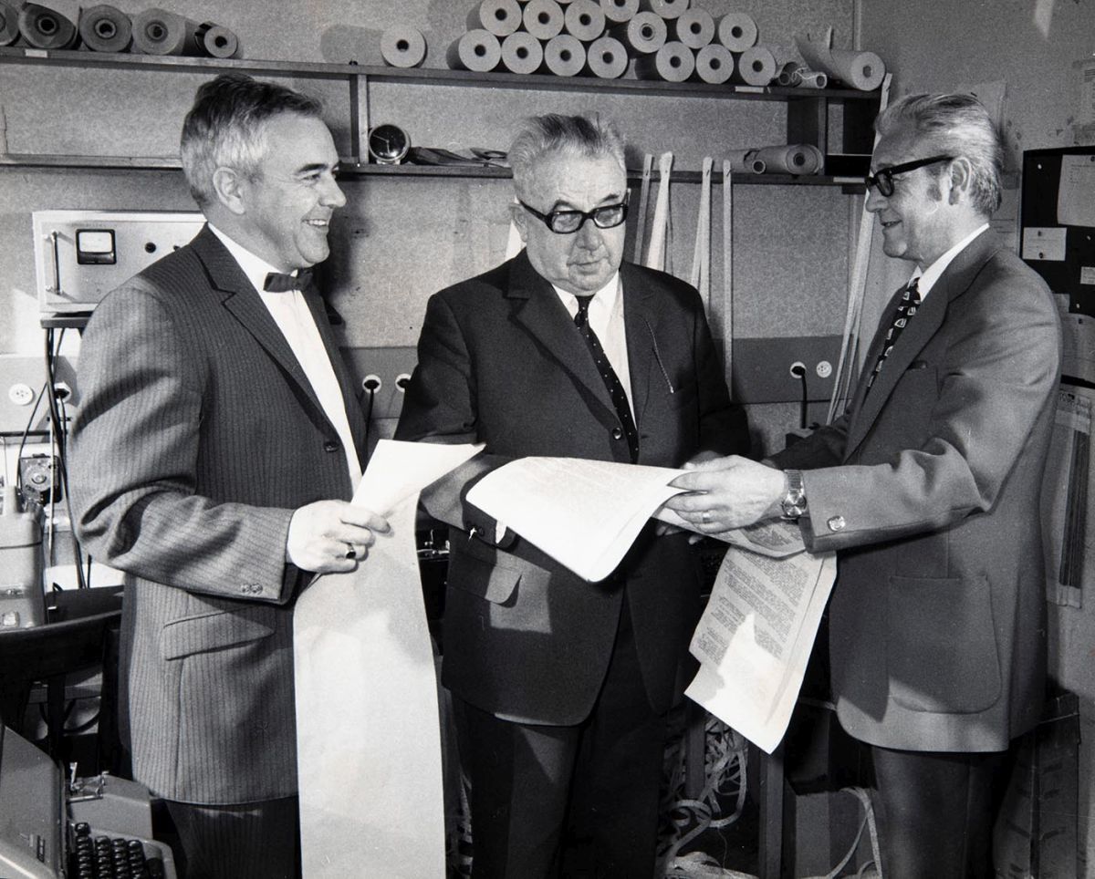 Arnold Wehrle (au centre) et ses fils et directeurs successifs Walter (à gauche) et Arnold jun. (à droite) dans la centrale télex de Sportinformation en mars 1972 à Zurich. Photo : KEYSTONE/ Photopress-Archives